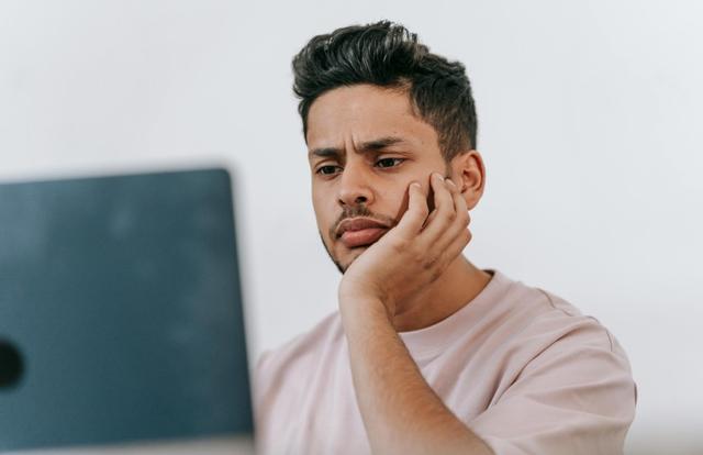 Frowning man working on laptop